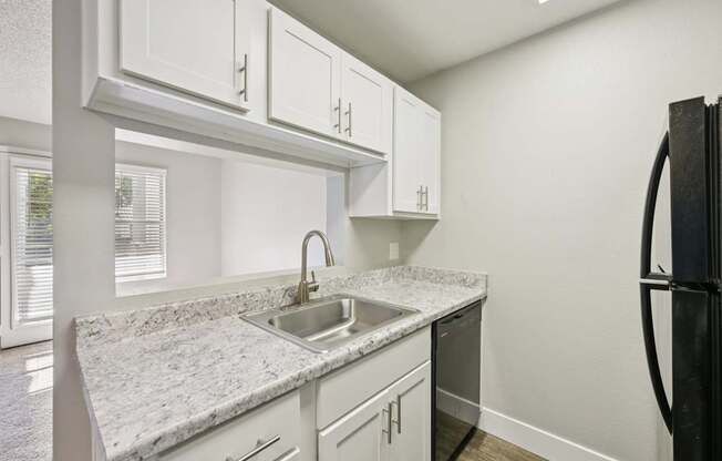 Model kitchen with white cabinets and a black refrigerator.