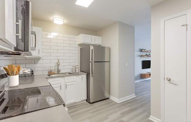 A kitchen with a refrigerator, stove, and sink.