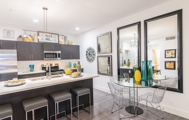 A kitchen with a dinning table and stools and ceiling light and island and oven and microwave and stove