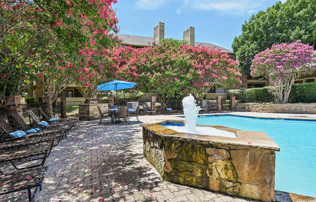 A pool area with a waterfall and a stone wall.
