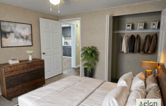 A bedroom with a bed, dresser, and coat rack.