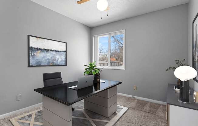 a home office with a large window and a ceiling fan