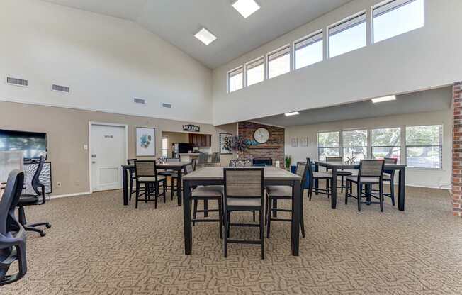 A large room with tables and chairs and a brick fireplace.