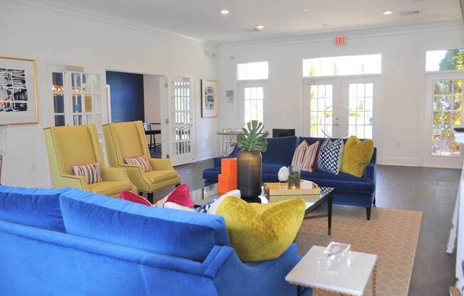 A living room with blue couches and yellow chairs.