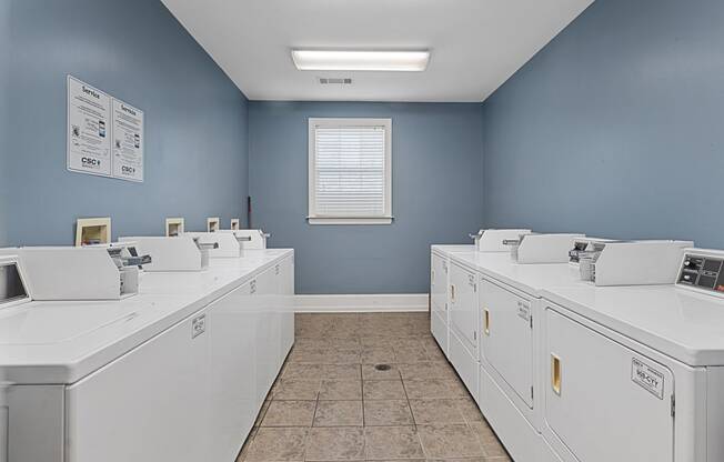 a row of washing machines in a laundry room with blue walls