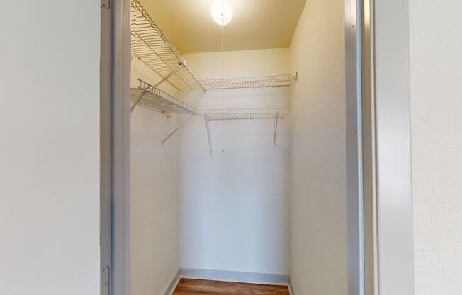a walk in closet with a white wall and a ceiling light