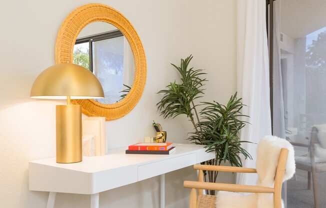 a white desk with a gold lamp and a chair in a room with a sliding glass door