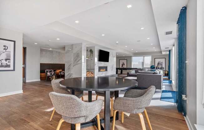 A modern dining room with a black table and grey chairs.