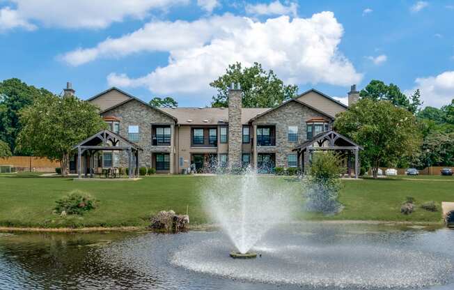 a fountain in the pond with a building in the background