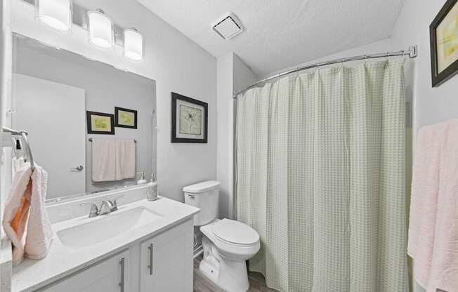 A white bathroom with a toilet, sink, and shower curtain.