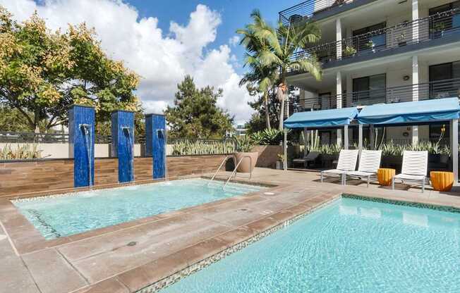 A swimming pool with a blue umbrella and chairs.