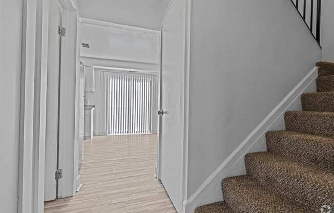 the landing of a staircase leading to a hallway with a door to a living room