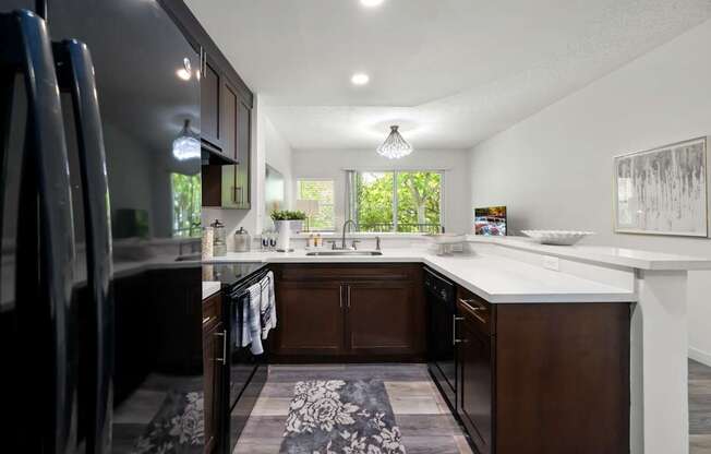 a kitchen with white countertops and dark cabinets and a black refrigerator