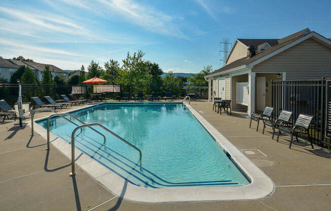 a swimming pool with chairs and a building with a house