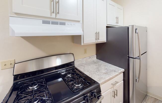 renovated kitchen with white cabinets and a gas stove and refrigerator