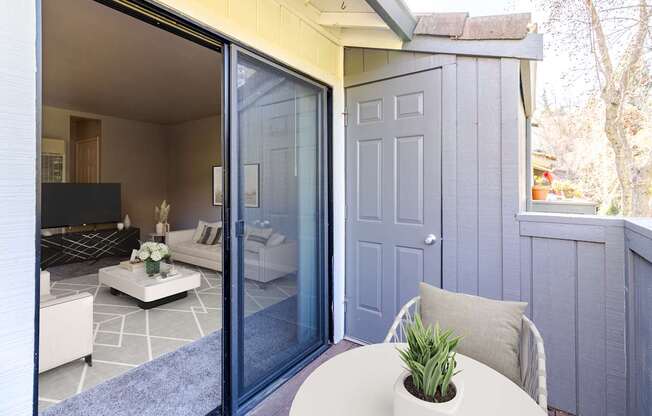 A white table with a plant on it sits in front of a grey door.
