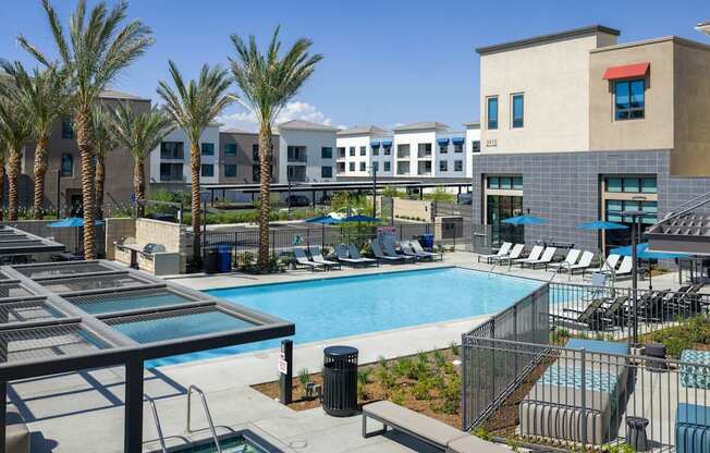 A pool surrounded by palm trees and lounge chairs.