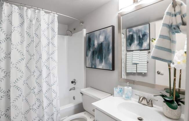 a white bathroom with a shower curtain and a sink and a toilet