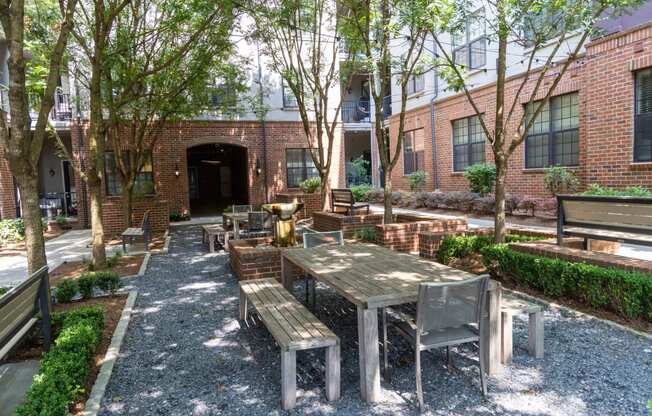 a courtyard with wooden tables and benches in front of a brick building