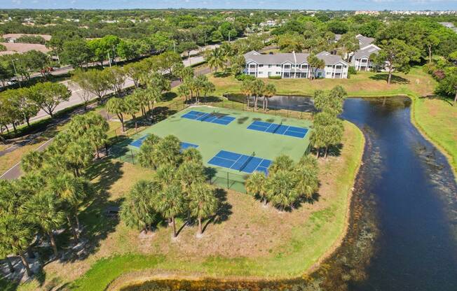 a tennis court with a house on the side of a lake