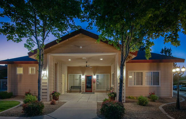 the front of a building at night with trees and a sidewalk