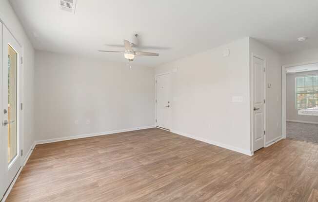 an empty living room with wood flooring and a ceiling fan