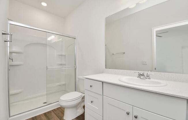 A white bathroom with a toilet, sink, and shower.