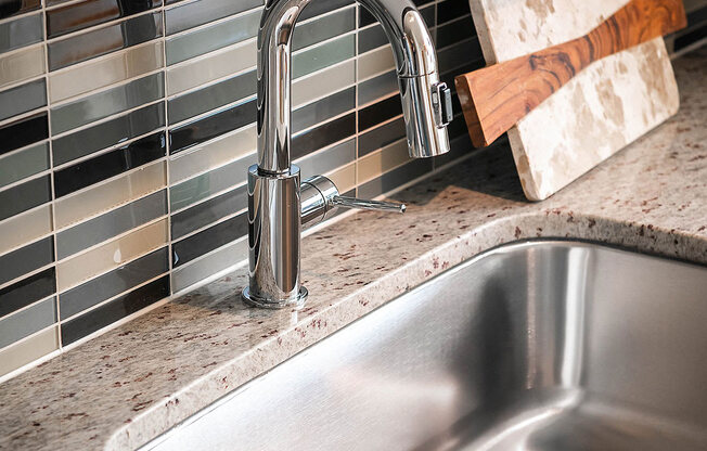 A kitchen sink with a chrome faucet and a tile backsplash.