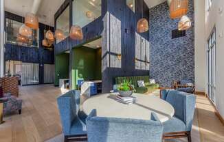 a communal area with a round table with blue chairs and a green couch in the background