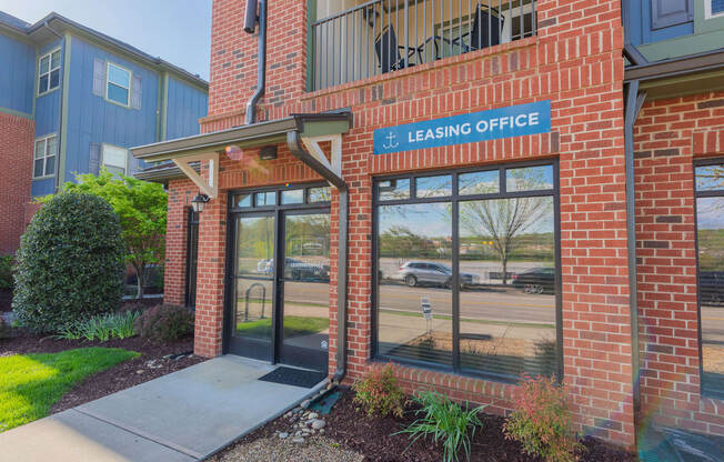 the entrance to the leasing office of a brick building with glass doors