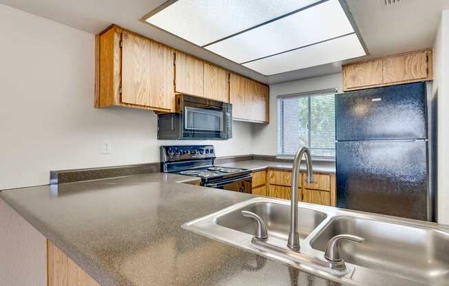 A kitchen with a stainless steel sink and wooden cabinets.