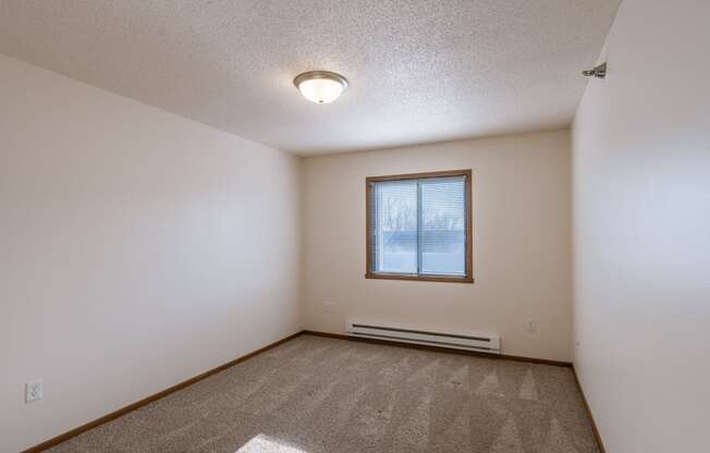 a bedroom with carpet and a window. Fargo, ND Eagle Run Apartments