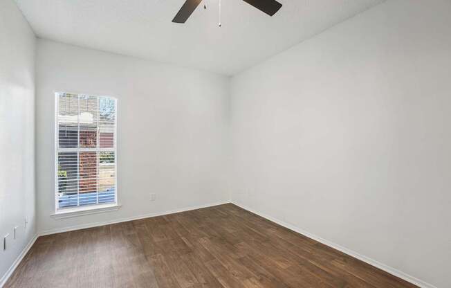 Empty room with a window and a ceiling fan.