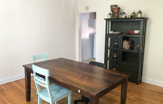 A wooden table with a blue chair in front of a black bookshelf.