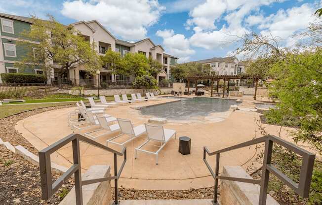 A small pool surrounded by a concrete patio and a metal railing.
