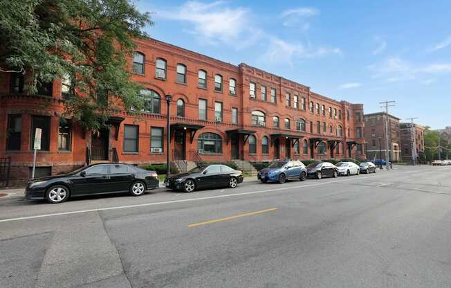 a row of red brick buildings with cars parked in front of them