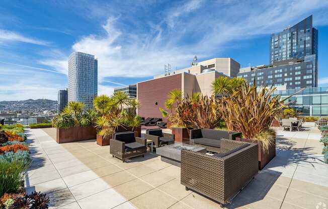 A rooftop patio with furniture and plants.
