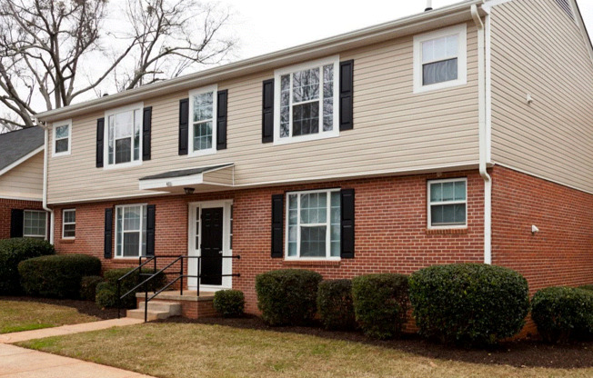 a brick house with black shutters and a black front door