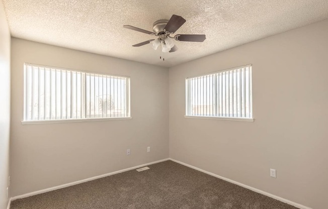 a bedroom with two windows and a ceiling fan