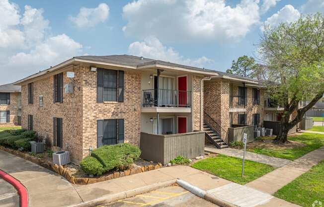 a brick apartment building with a red door and a sidewalk