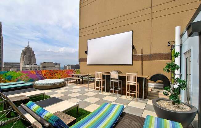 a rooftop terrace with tables and chairs and a projection screen