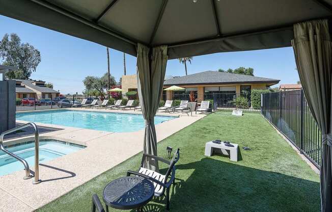 a backyard with a pool and a patio with chairs and a table