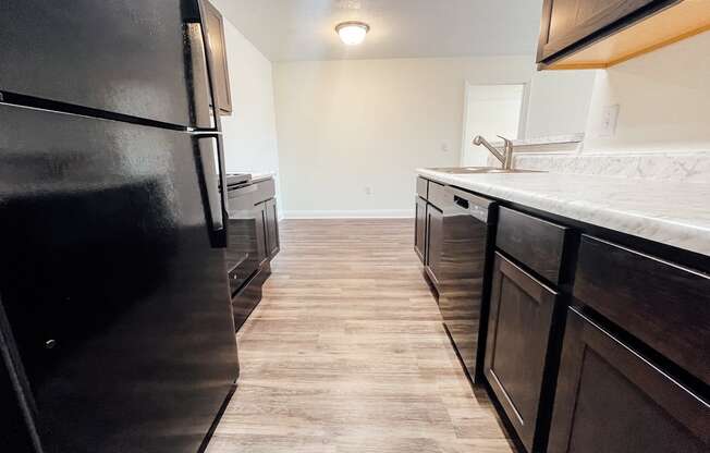 an empty kitchen with black appliances and a white counter top