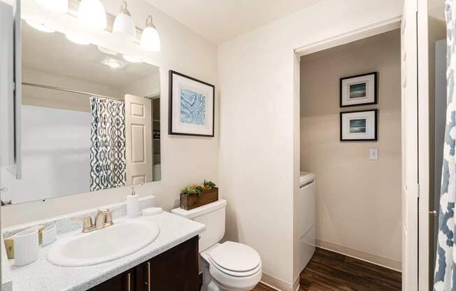 A bathroom with a toilet, sink, and mirror.