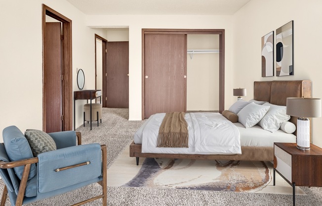 A bedroom with a bed, chair, and two doors.