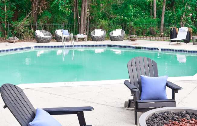 the pool is next to two chairs and a fire pit