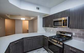 Colton Apartments  kitchen with dark cabinets, white countertops and stainless steel appliances