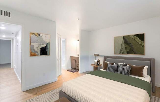 A bedroom with a large bed and two paintings on the wall.
