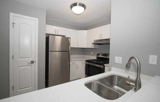 a kitchen with white cabinets and stainless steel appliances at Evergreen Luxury Apartments, Merrillville, Indiana