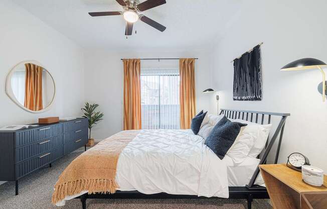 A bedroom with a bed, dresser, and ceiling fan.